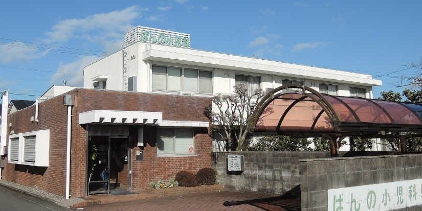 ばんの小児科の外観。レンガ造りの建物と、屋根付きの駐輪・駐車スペース